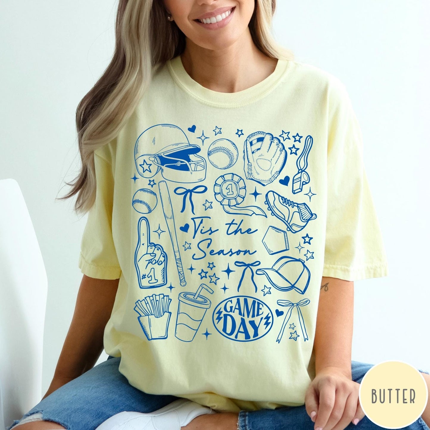Comfort Colors tee in Butter featuring baseball game day graphic with helmet, bat, ball, and snacks.