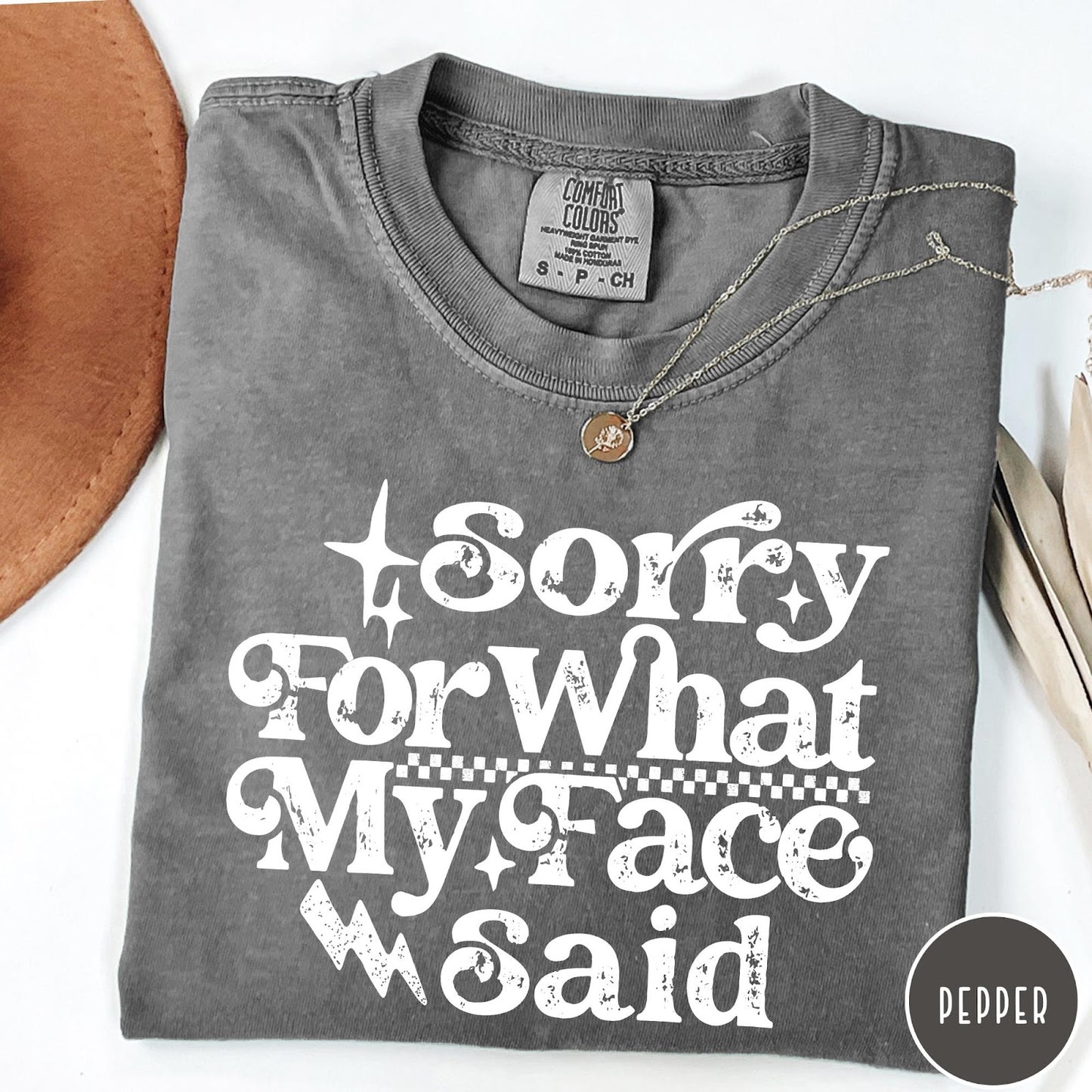 Comfort Colors tee in Pepper featuring sarcastic expression graphic Sorry for What My Face Said in white