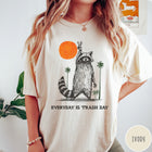 Comfort Colors tee in Ivory featuring vintage style graphic of a raccoon making a peace sign