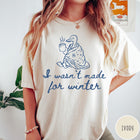 Comfort Colors tee in Ivory featuring line art graphic of a duck wrapped in a blanket drinking coffee