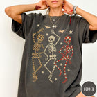 Comfort Colors tee in Pepper featuring dancing skeletons design with three skeletons, stars, and bats graphic