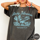 Comfort Colors tee in Pepper featuring vintage style graphic of an elk standing in front of mountains
