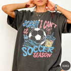 Comfort Colors tee in Pepper featuring screen print style soccer season graphic with ball and iced coffee