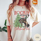 Comfort Colors tee in Ivory featuring western graphic design of a cowboy on a bucking horse Christmas tree