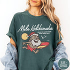 Comfort Colors tee in Blue Spruce featuring vintage style graphic of a surfing Santa Claus on vacation