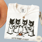 Comfort Colors tee in Ivory featuring illustrated style graphic of four cats in robes around a candle