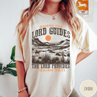 Comfort Colors tee in Ivory featuring desert landscape graphic with a rider and sun design.