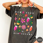 Comfort Colors tee in Pepper featuring New Year celebration graphic with champagne bottles, glasses, and disco ball