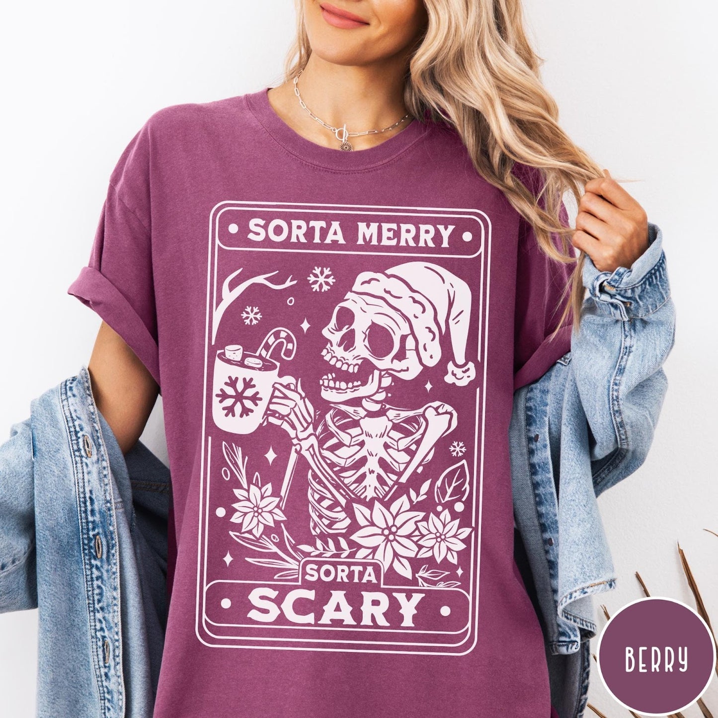 Comfort Colors tee in Berry featuring graphic illustration of a skeleton in a Santa hat holding cocoa