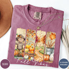 Comfort Colors tee in Berry featuring autumn harvest graphic with a scarecrow, pumpkins, and fall foliage scenes
