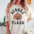 Comfort Colors tee in Ivory featuring retro style graphic with a smiling pumpkin and Spooky Vibes text