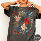 Comfort Colors tee in Pepper featuring winter florals graphic with poinsettias, holly leaves, and red berries.