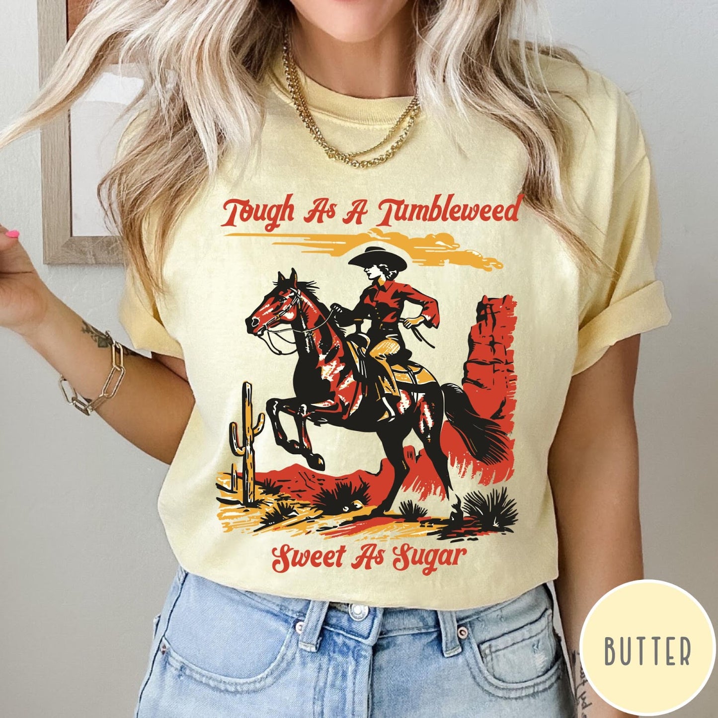 Comfort Colors tee in Butter featuring western style graphic of a cowgirl riding a horse in desert