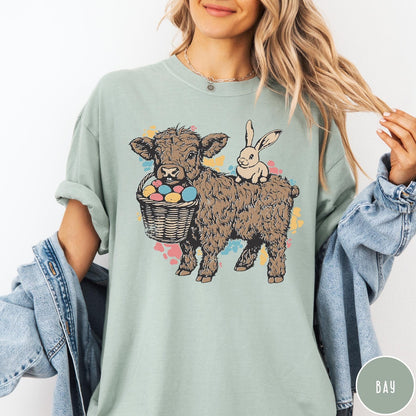 Comfort Colors tee in Bay featuring graphic style illustration of a Highland cow with bunny and eggs