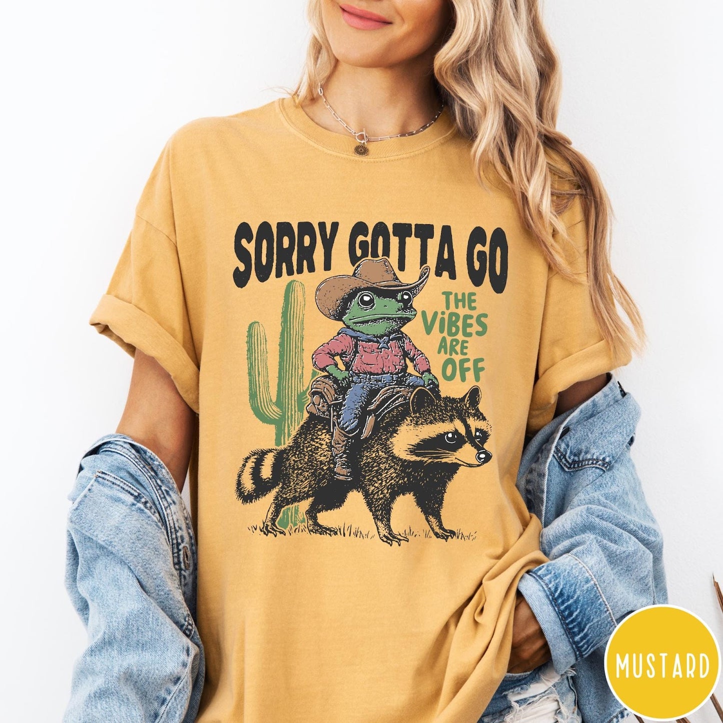 Comfort Colors tee in Mustard featuring western graphic of a cowboy frog riding a raccoon with cactus
