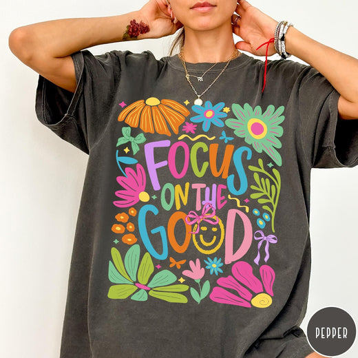 Comfort Colors tee in Pepper featuring positivity typography and floral collage graphic with a smiley face.