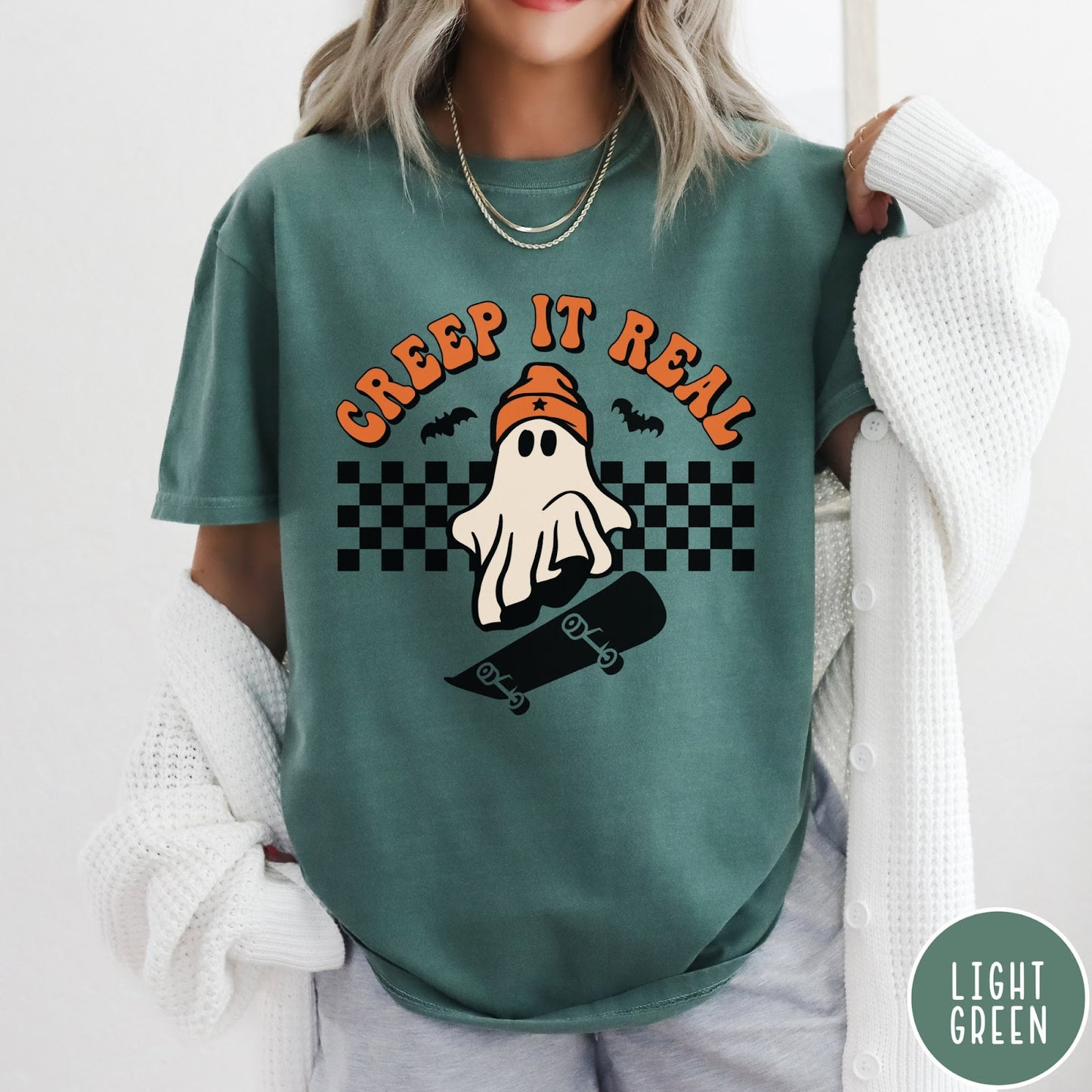 Comfort Colors tee in Light Green featuring retro style ghost graphic with skateboard and checkered background pattern