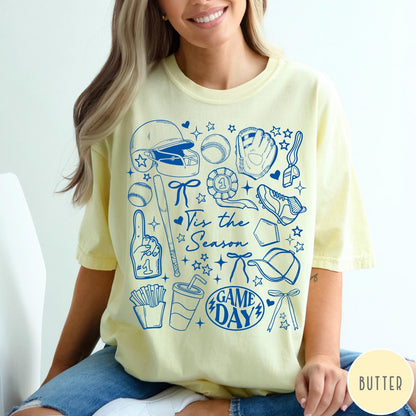 Comfort Colors tee in Butter featuring baseball game day graphic with helmet, bat, ball, and snacks.