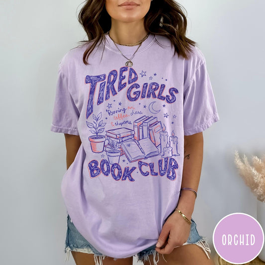 Comfort Colors tee in Orchid featuring book club design with stacks of books, plants, and candles.
