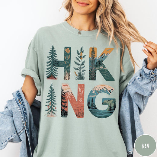Comfort Colors tee in Bay featuring nature graphic with trees and mountains inside the word Hiking