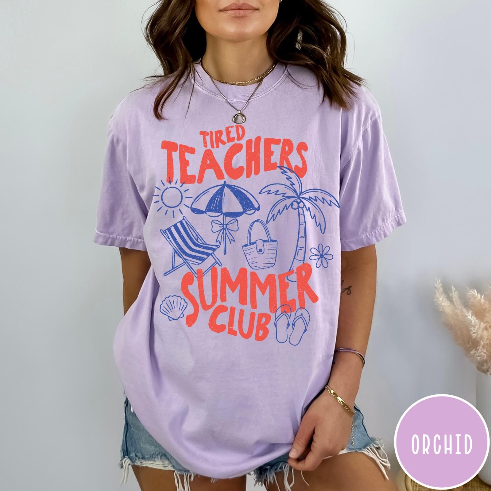Comfort Colors tee in Orchid featuring summer vacation graphic with beach umbrella, palm tree, and beach chair.
