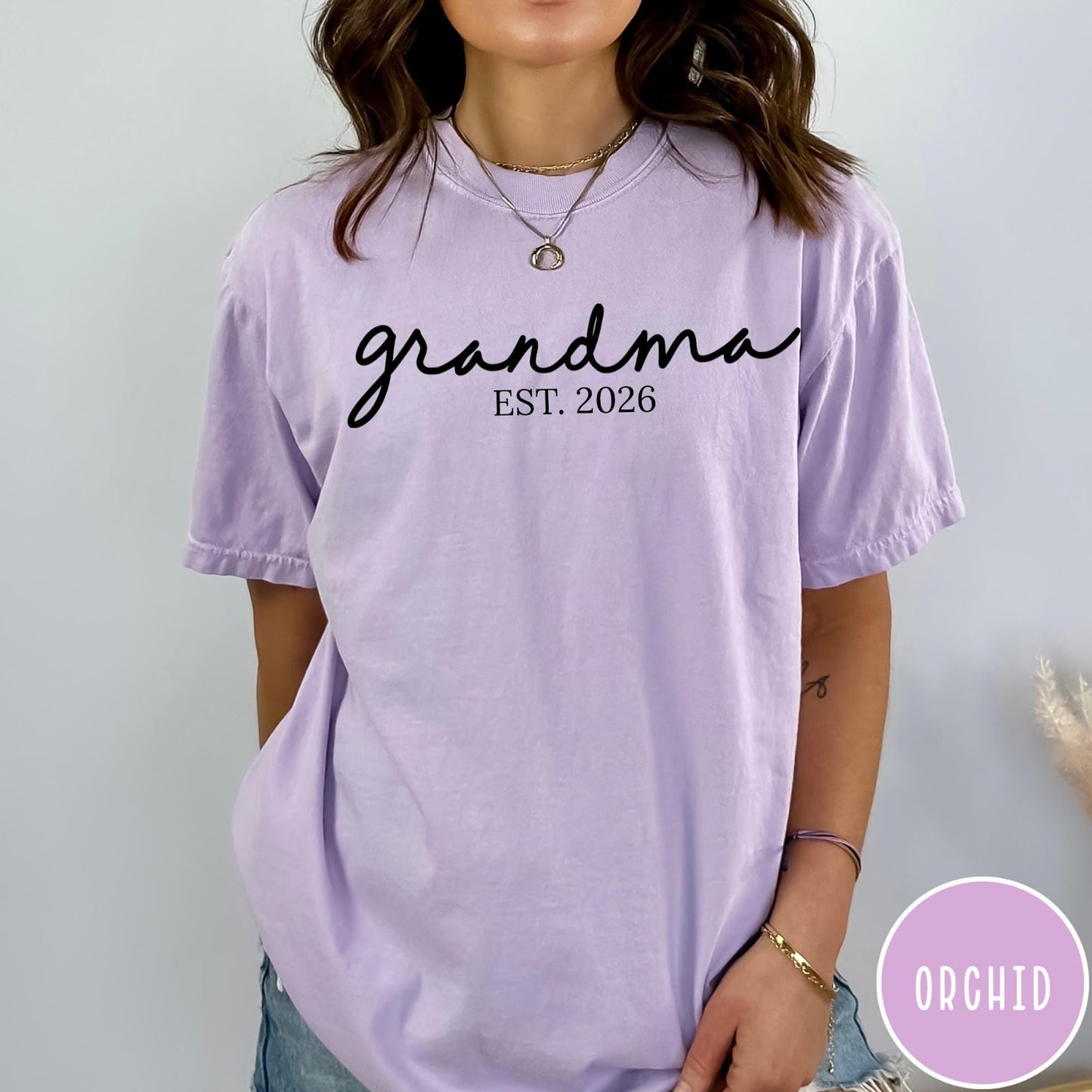 Comfort Colors tee in Orchid featuring cursive Grandma Est 2026 text in a clean black graphic style