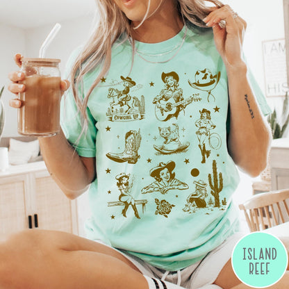 Comfort Colors tee in Island Reef featuring retro western collage graphic with cowgirls, boots, and desert elements