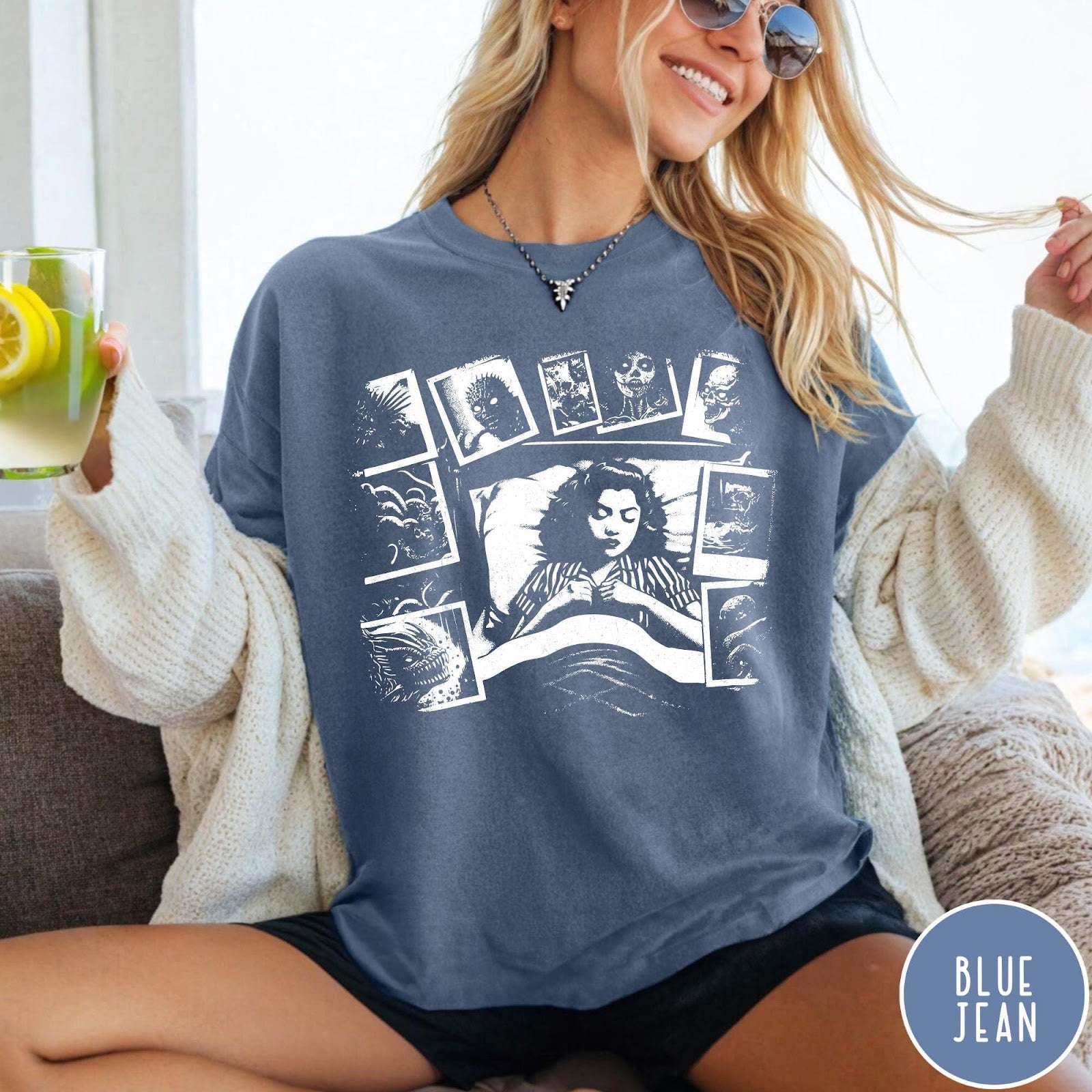 Comfort Colors tee in Blue Jean featuring graphic style illustration of a woman sleeping surrounded by horror polaroids