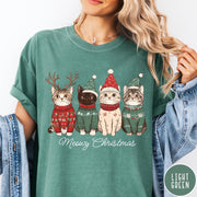 Comfort Colors tee in Light Green featuring holiday graphic of four cats wearing Christmas sweaters and hats
