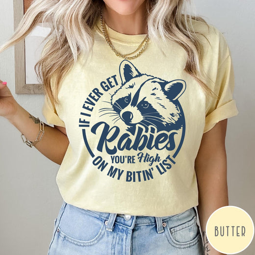 Comfort Colors tee in Butter featuring screen print style graphic of a raccoon with funny rabies text