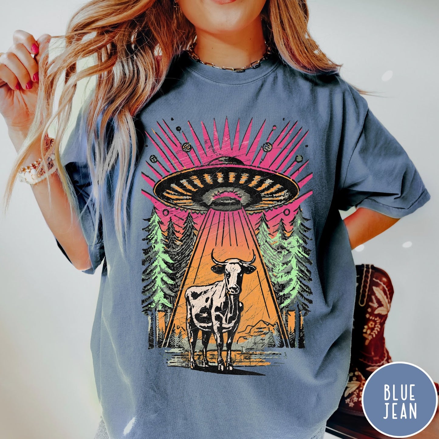 Comfort Colors tee in Blue Jean featuring graphic style cow being abducted by a UFO in the forest