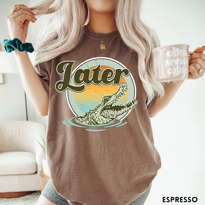 Comfort Colors tee in Espresso featuring vintage style graphic of an alligator emerging from water with sunset background