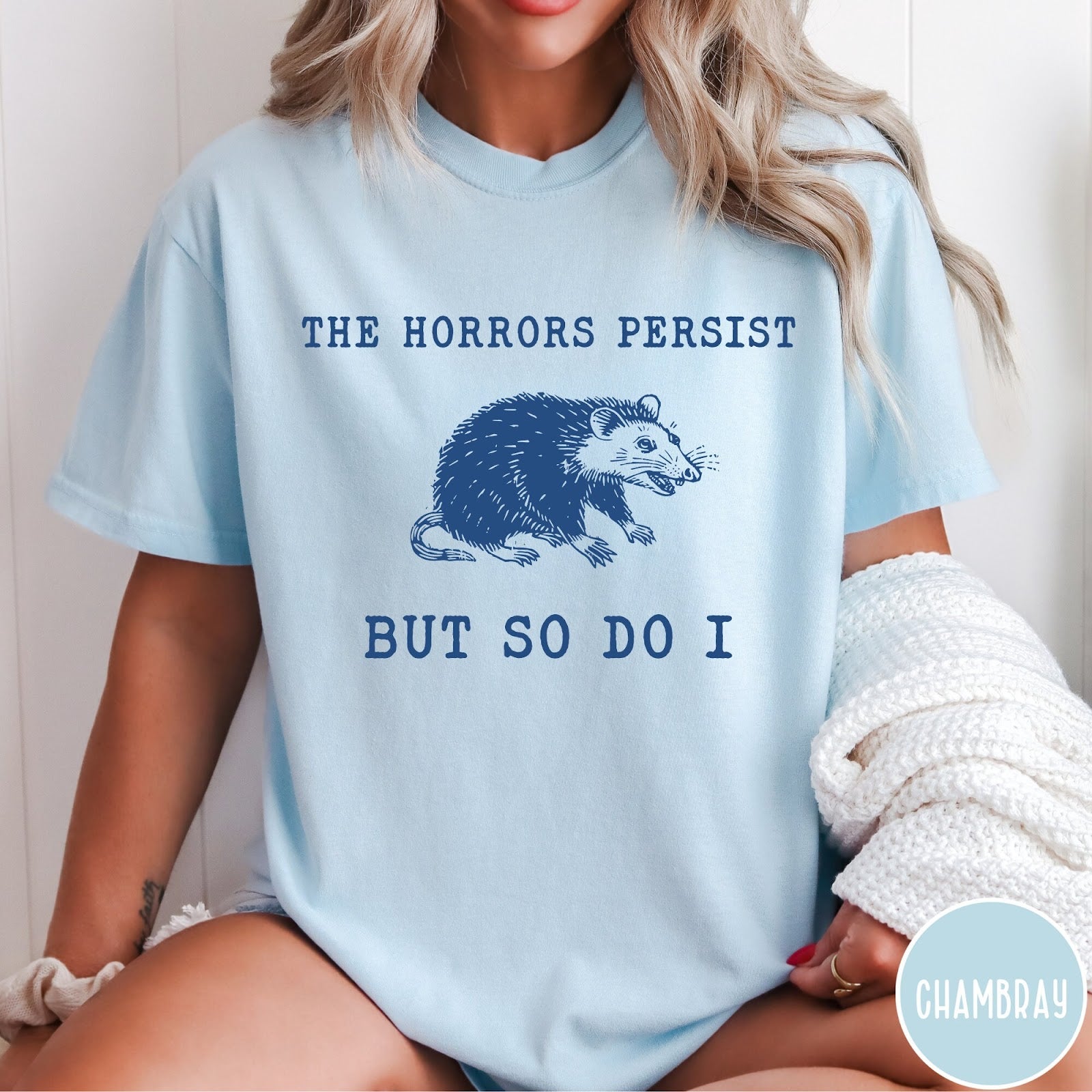 Comfort Colors tee in Chambray featuring illustrative style opossum graphic with text The Horrors Persist But So Do I