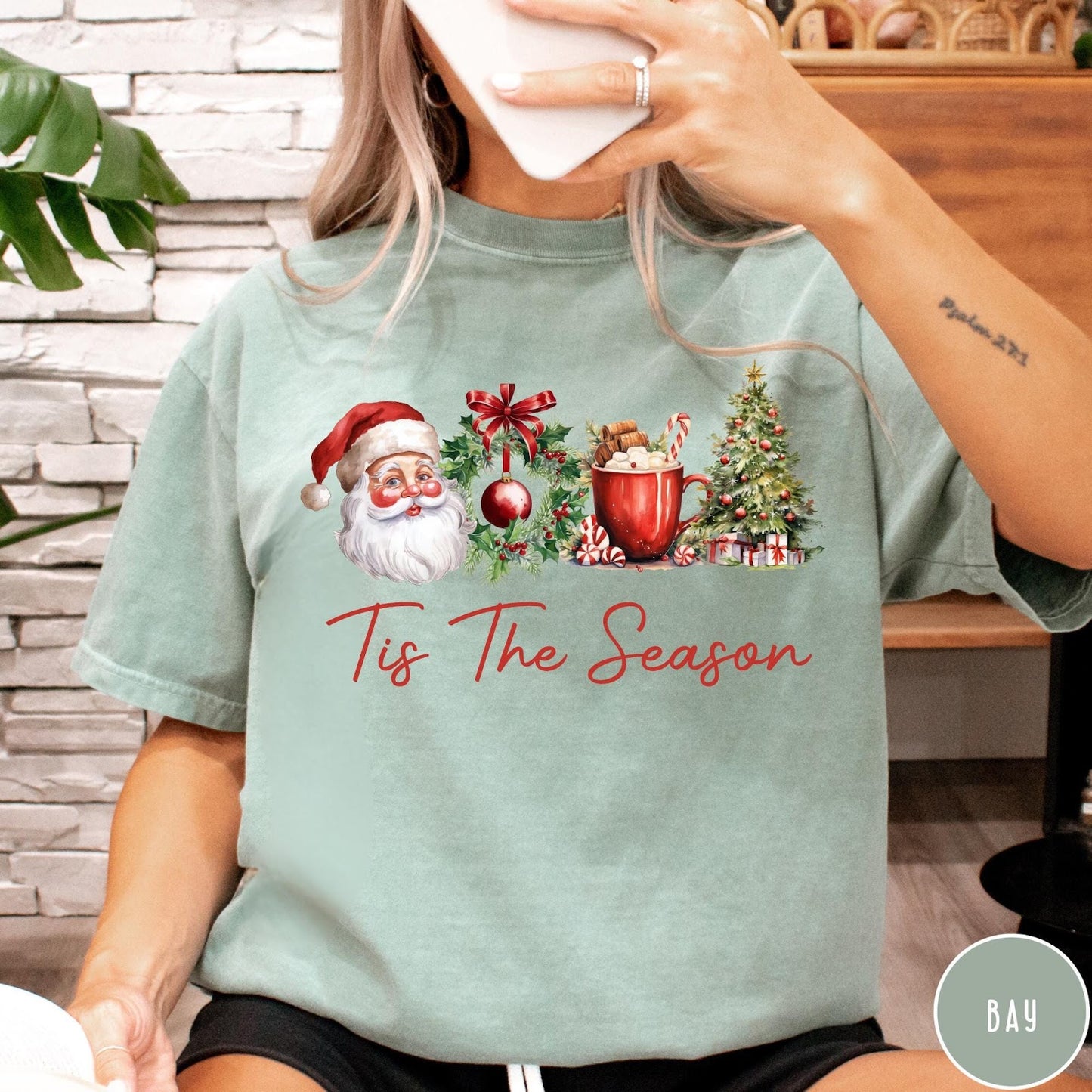 Comfort Colors tee in Bay featuring holiday design with Santa, wreath, hot cocoa, and Christmas tree graphic
