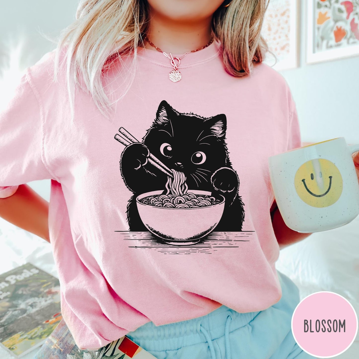Comfort Colors tee in Blossom featuring graphic illustration of a cute black cat eating a bowl of ramen