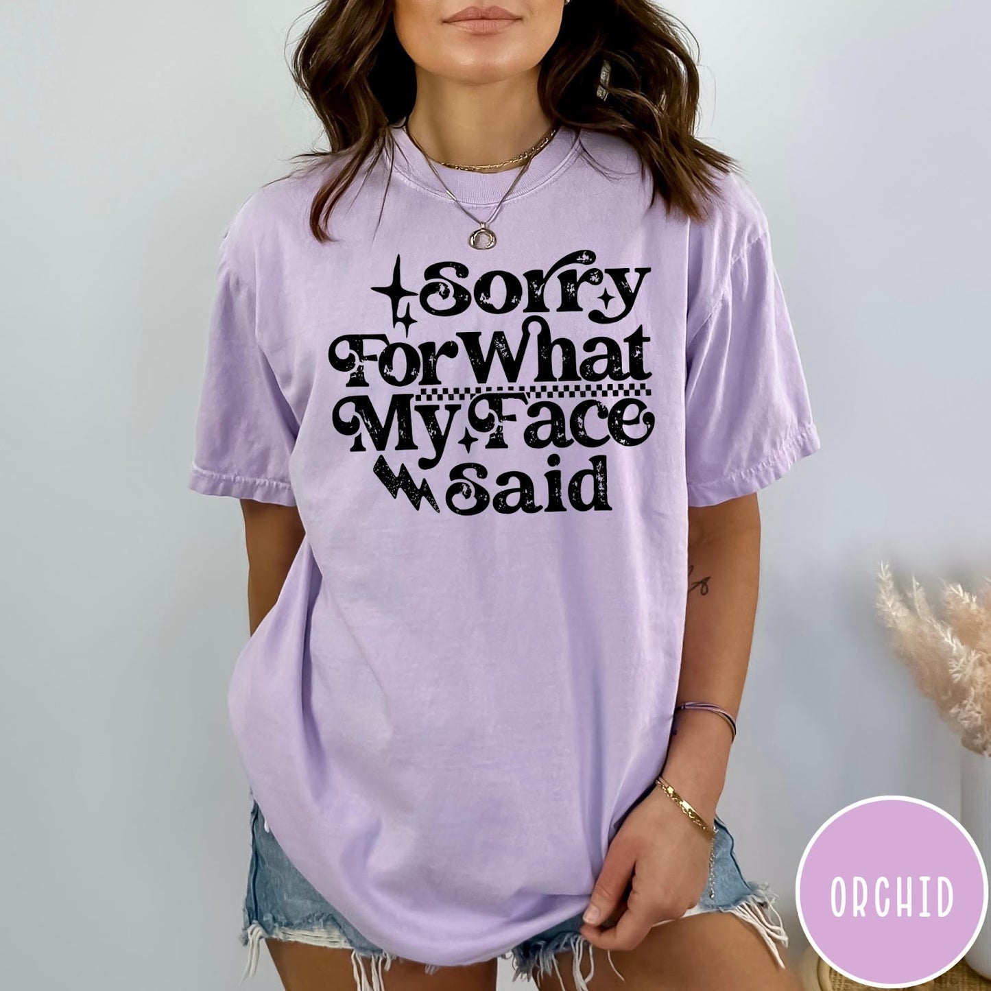 Comfort Colors tee in Orchid featuring sarcastic expression graphic Sorry for What My Face Said in black