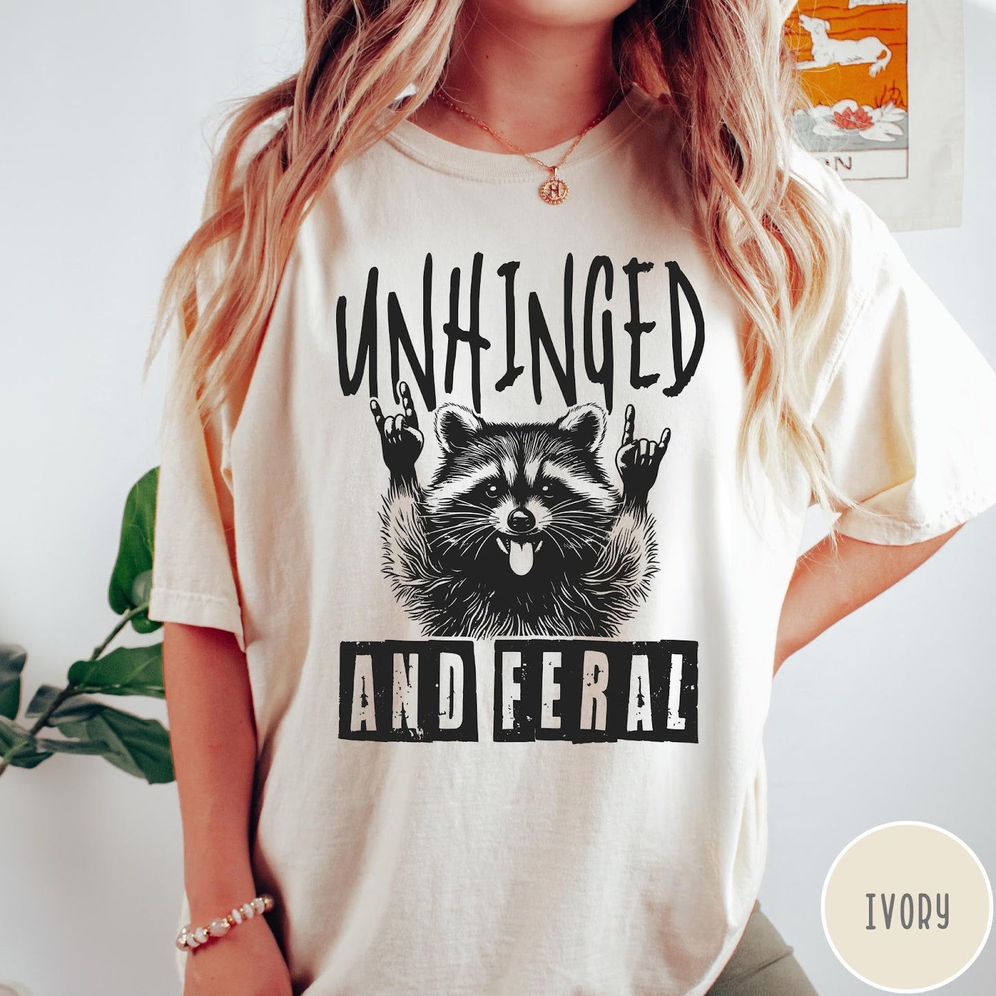 Comfort Colors tee in Ivory featuring graphic style raccoon with tongue out and rock and roll hands