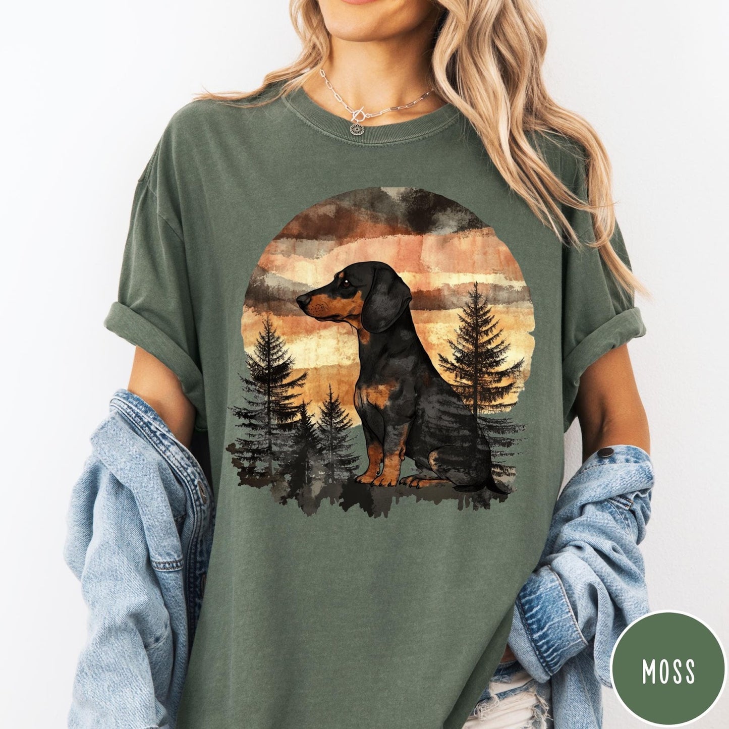 Comfort Colors tee in Moss featuring vintage style dachshund dog graphic with forest and sunset background