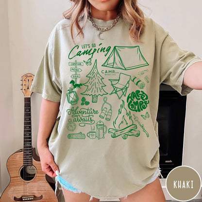 Comfort Colors tee in Khaki featuring retro camping adventure collage graphic with tent, campfire, and outdoor icons