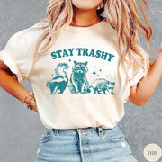 Comfort Colors tee in Ivory featuring graphic style raccoon, skunk, and opossum wearing sunglasses with Stay Trashy text