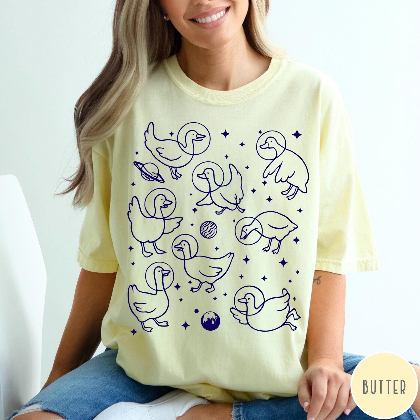 Comfort Colors tee in Butter featuring line art graphic of multiple geese wearing astronaut helmets in space