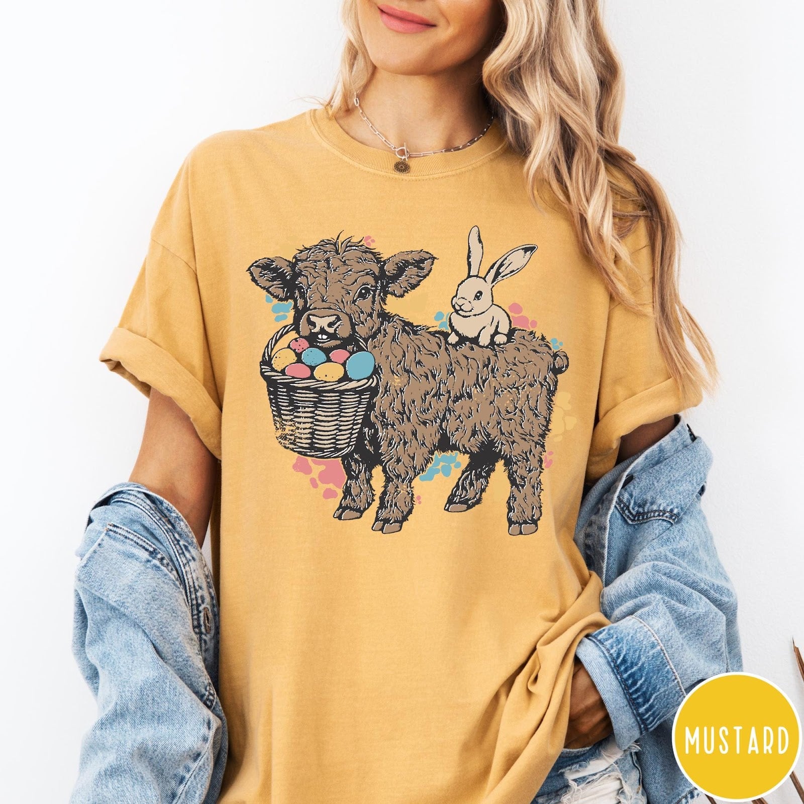 Comfort Colors tee in Mustard featuring graphic style Highland cow and bunny with an Easter egg basket