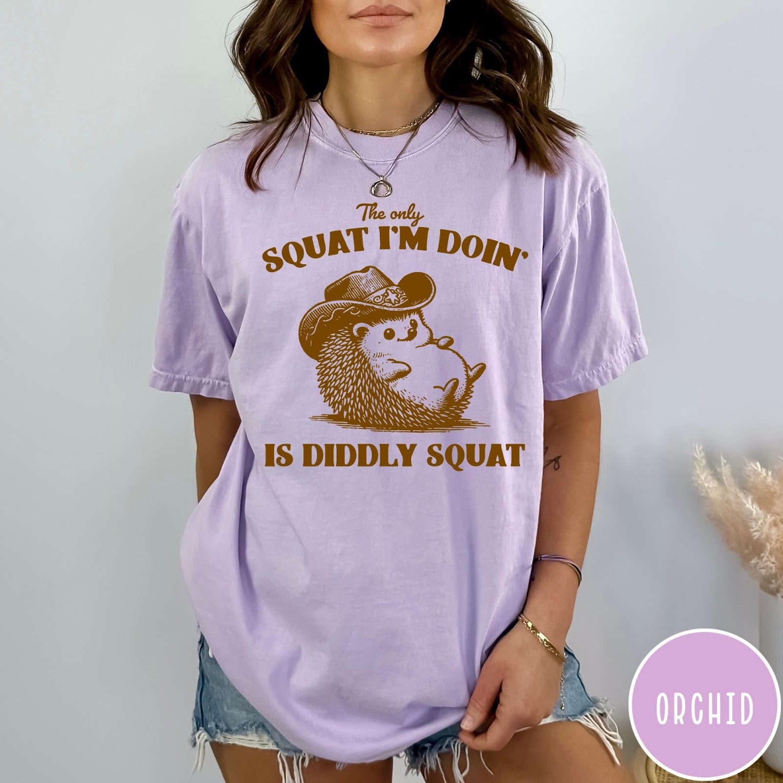 Comfort Colors tee in Orchid featuring cute graphic style illustration of a hedgehog wearing a cowboy hat