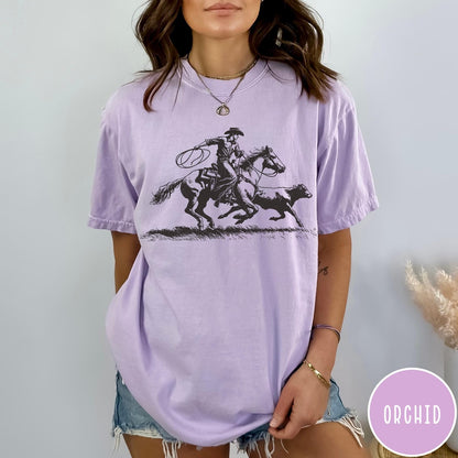 Comfort Colors tee in Orchid featuring western style graphic of a cowboy roping a calf on horseback