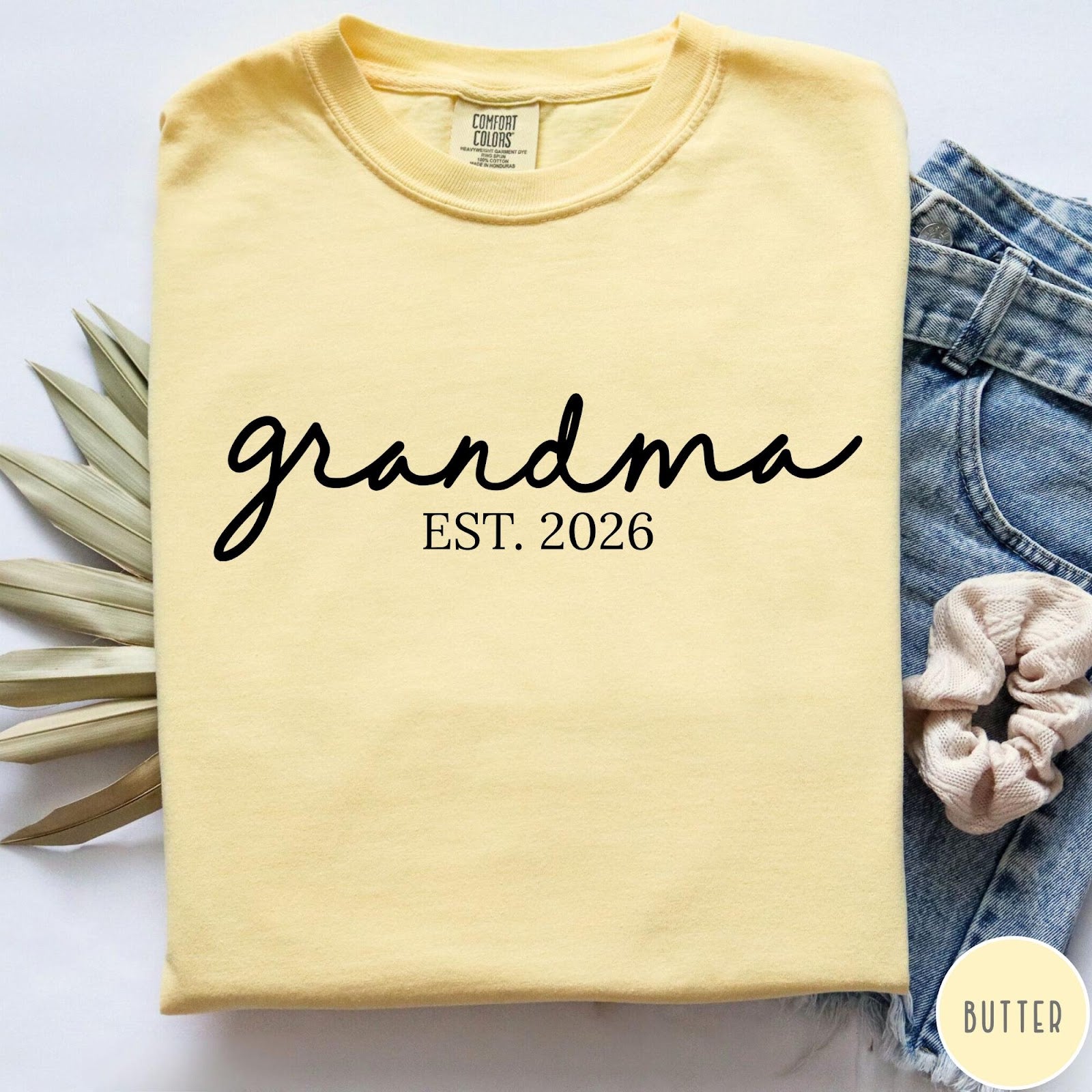 Comfort Colors tee in Butter featuring script design Grandma Est. 2026 announcement graphic in black