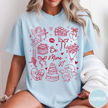Comfort Colors tee in Chambray featuring Valentine's Day collage graphic with cupid, cakes, and romantic symbols.