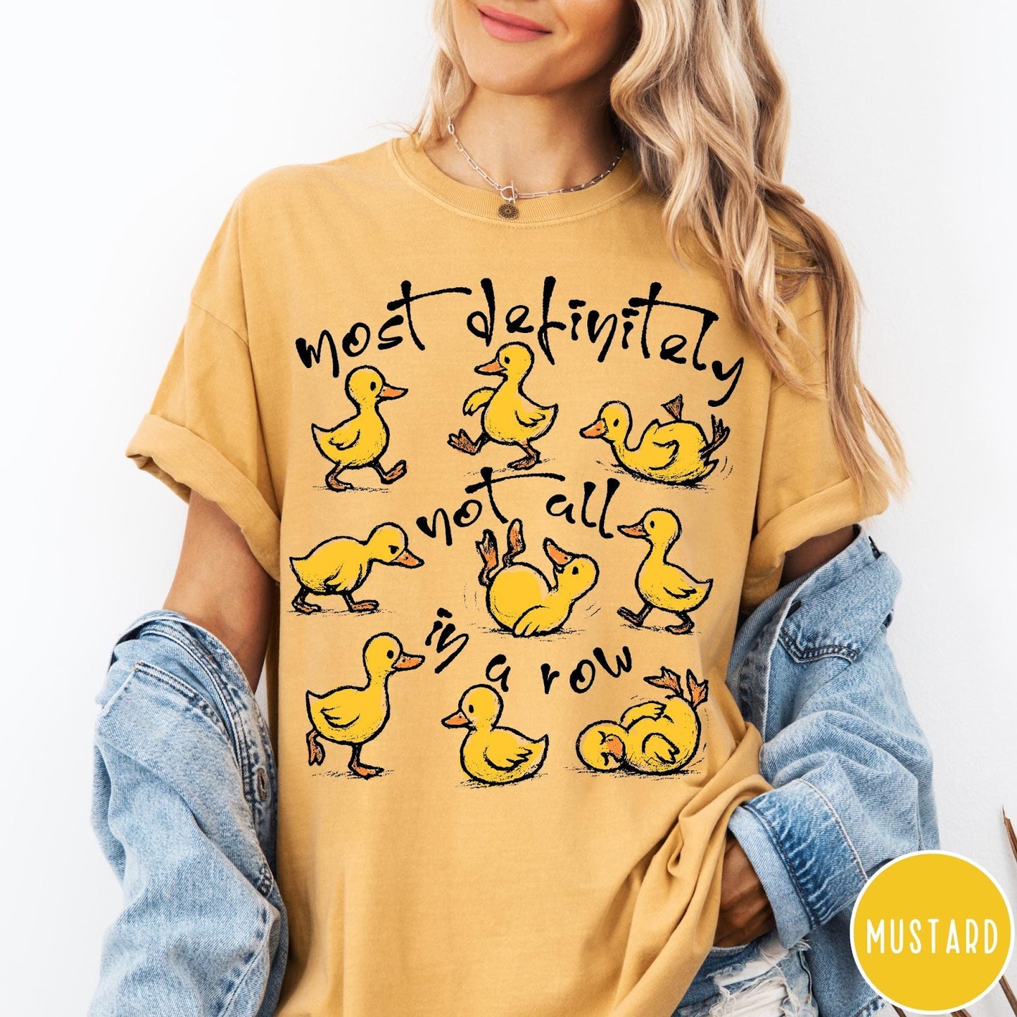 Comfort Colors tee in Mustard featuring whimsical duck graphic with text most definitely not all in a row.
