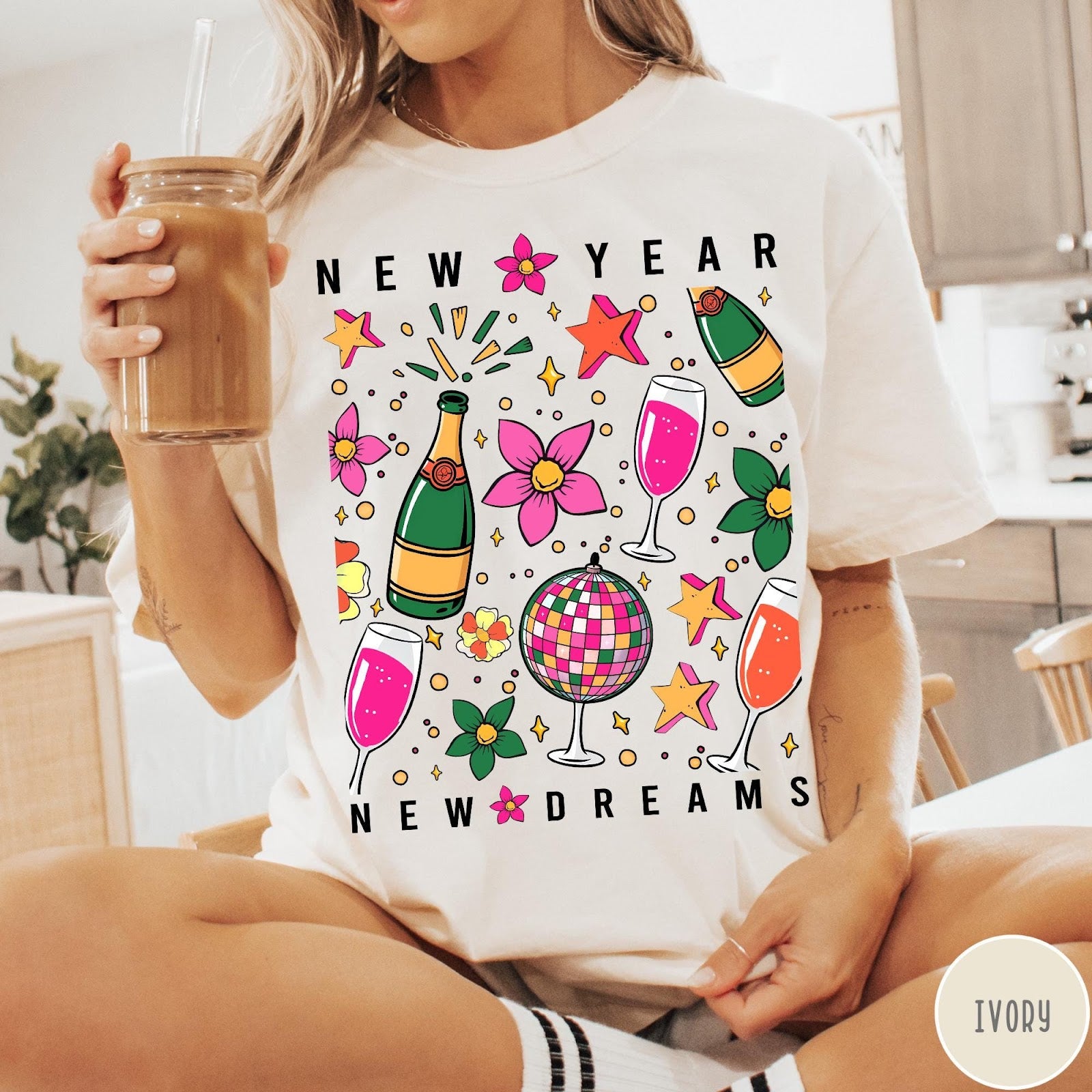 Comfort Colors tee in Ivory featuring New Year celebration graphic with champagne bottles, glasses, and disco ball