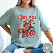 Comfort Colors tee in Bay featuring vintage style graphic of Santa Claus riding a bucking rodeo horse