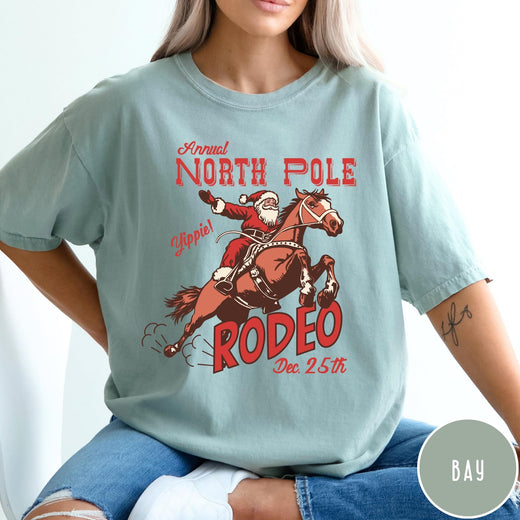Comfort Colors tee in Bay featuring vintage style graphic of Santa Claus riding a bucking rodeo horse